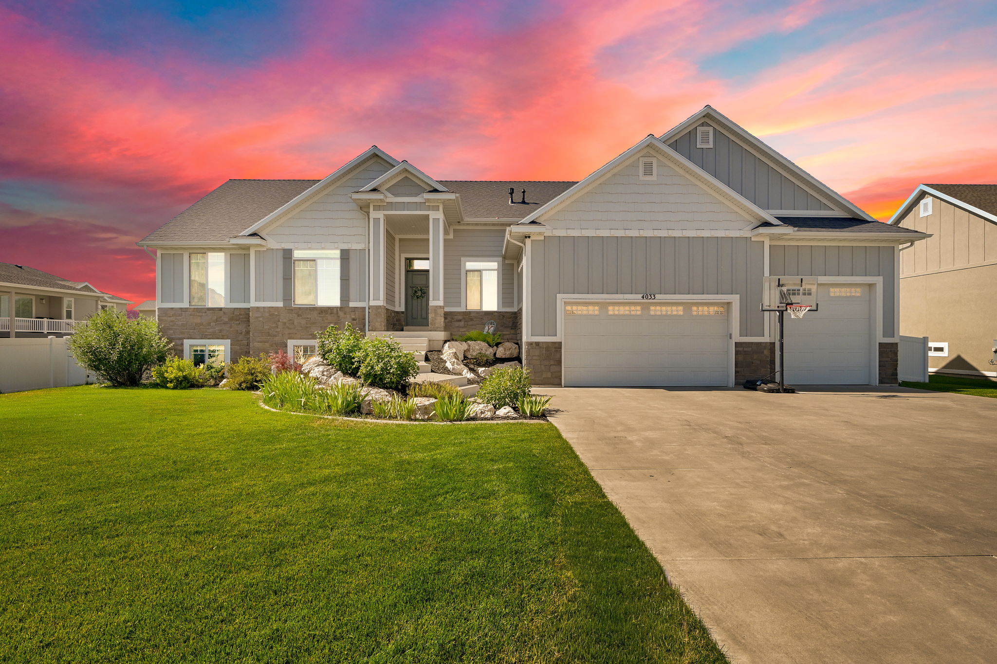 Exterior featuring light gray siding, stone veneer accents, and a covered entry