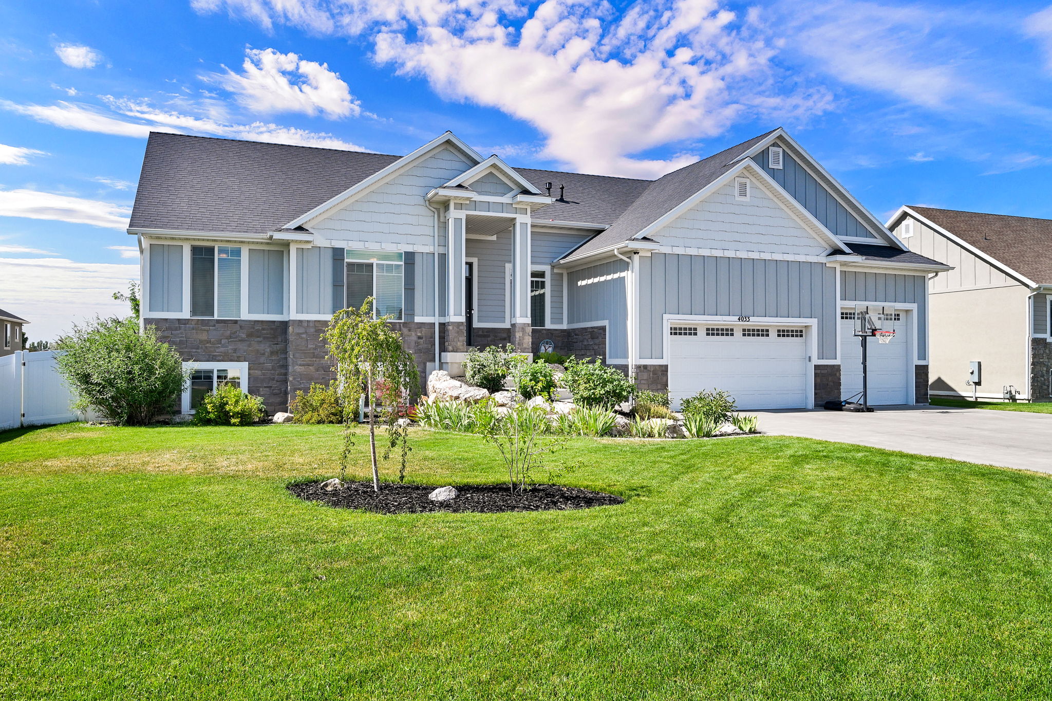 Contemporary home exterior with light blue vertical siding and dark stone veneer accents
