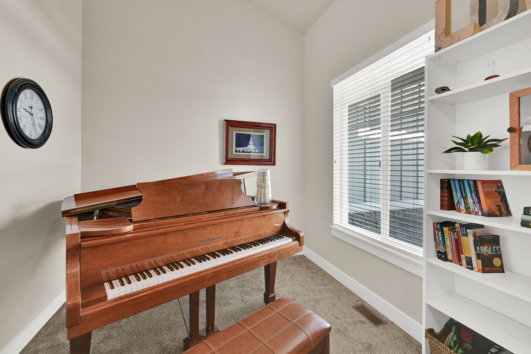 Carpeted room with a large window featuring horizontal blinds