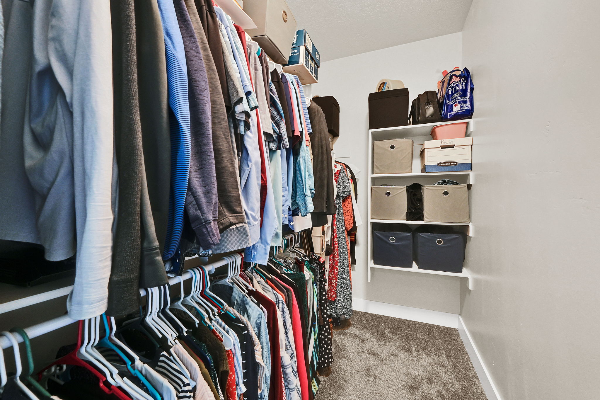 Walk-in closet featuring carpet flooring, built-in shelving, and multiple hanging rods for ample storage