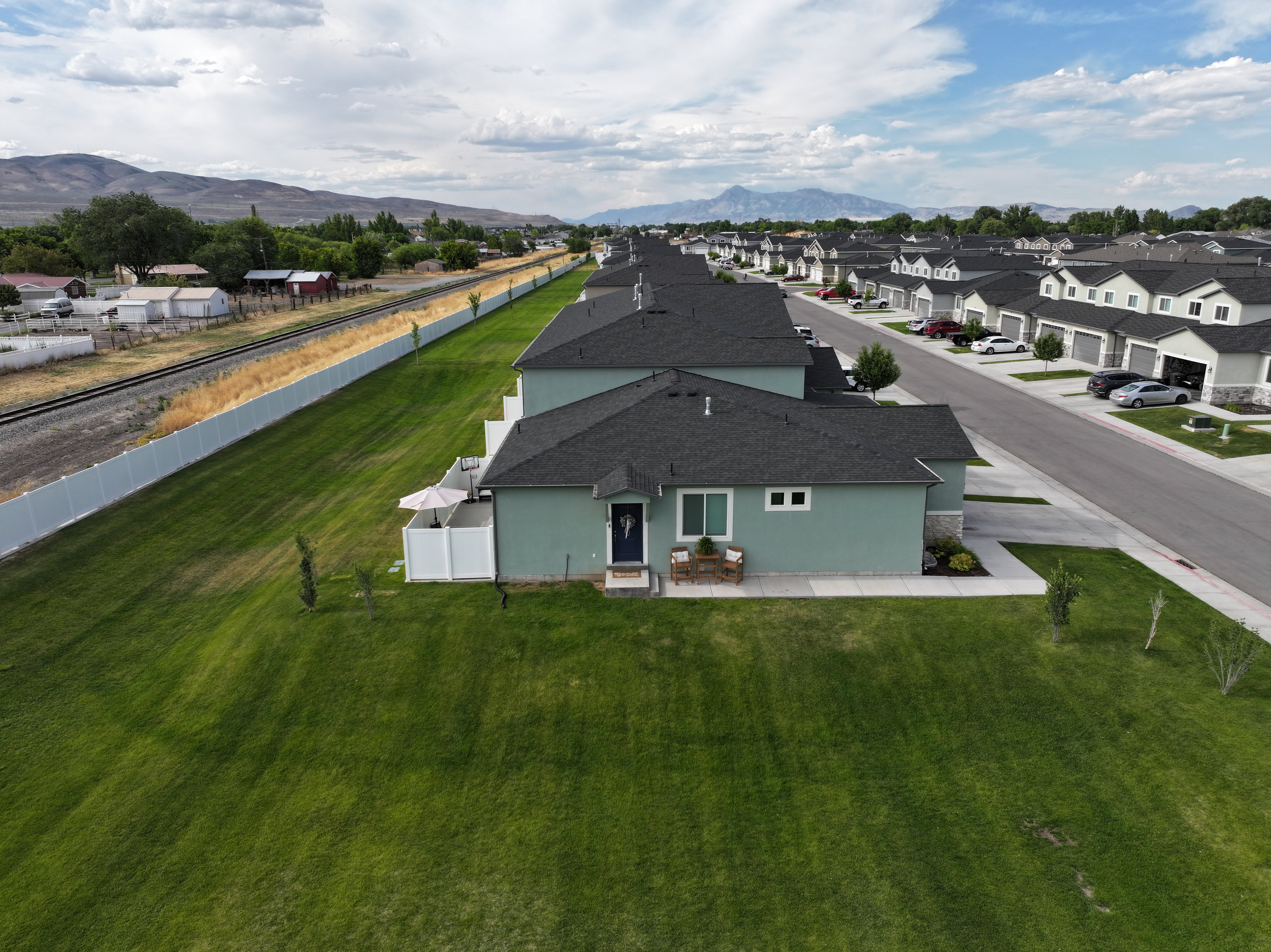 Fenced in private patio. Green stucco exterior, dark shingle roof, and a welcoming front porch.