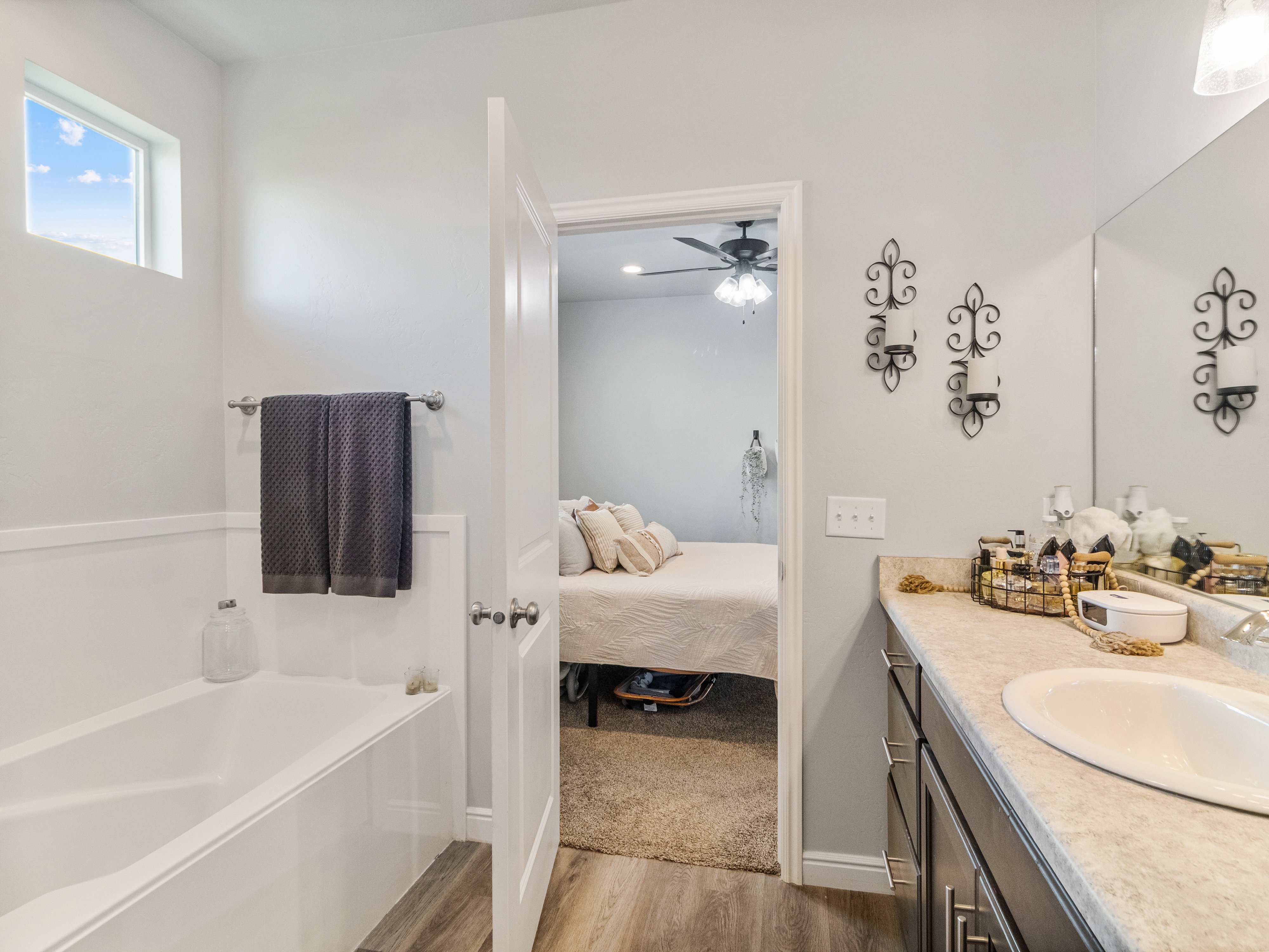 Bathroom featuring a built-in bathtub with wainscoting, wood-finish flooring, and an elevated window