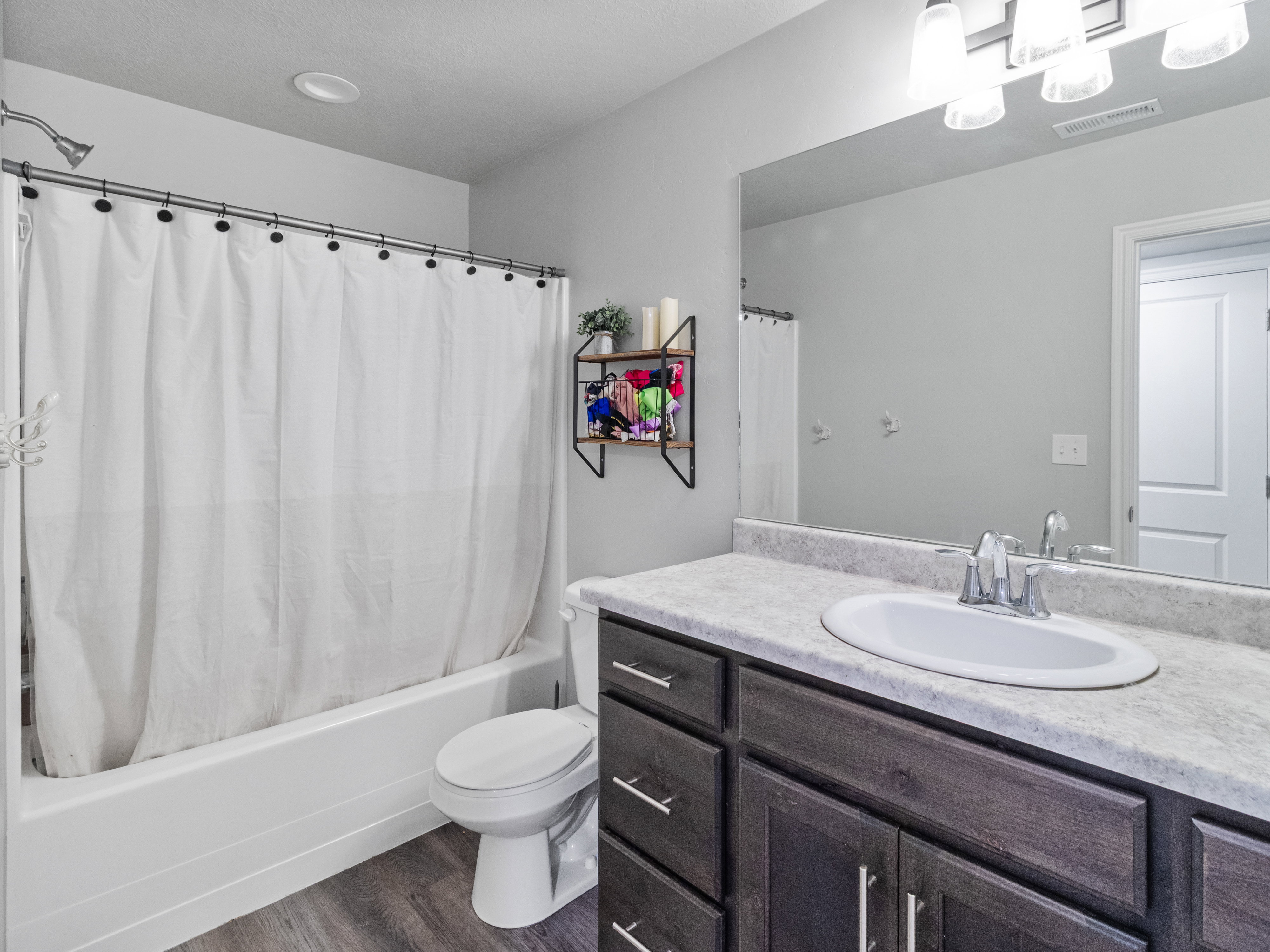 Bathroom featuring a spacious vanity with an integrated sink, dark wood-finish cabinetry, and a full-width mirror