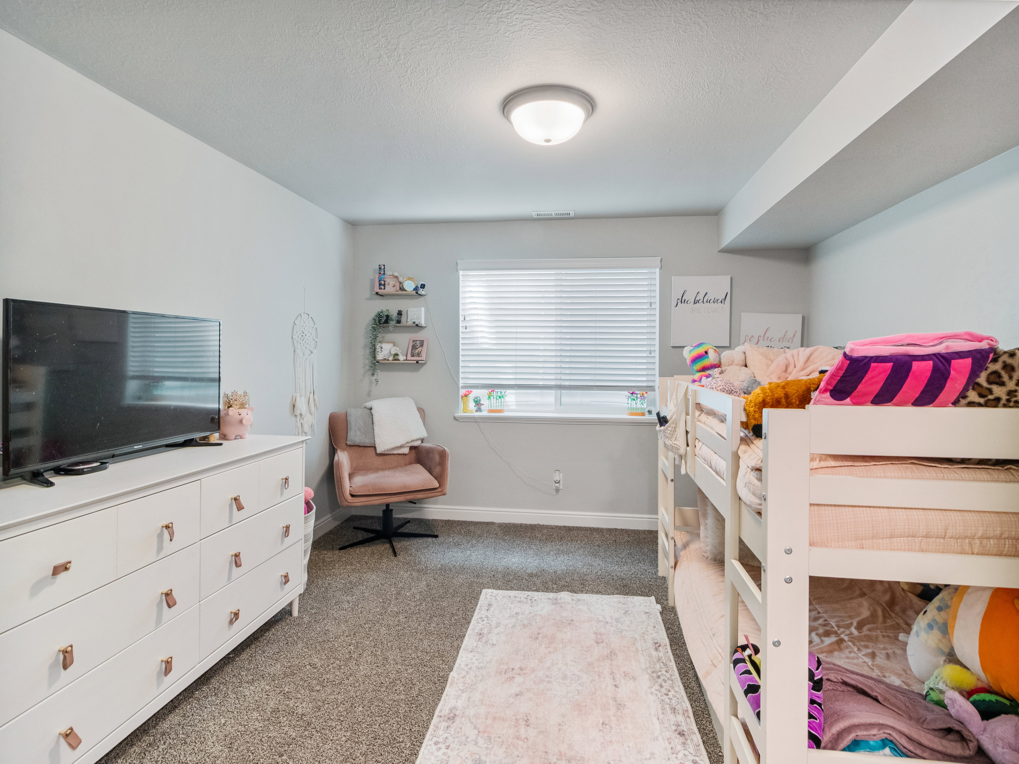 Recessed window with horizontal blinds, built-in shelving, carpeted flooring, and an overhead flush-mount light fixture