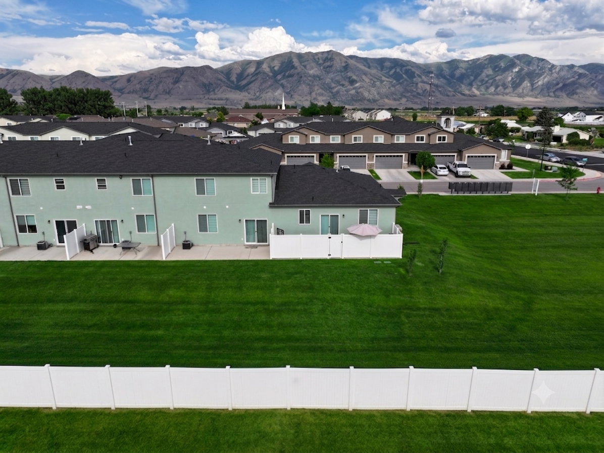 Rear patio with sliding glass door access to an expansive green space, bordered by a white privacy fence