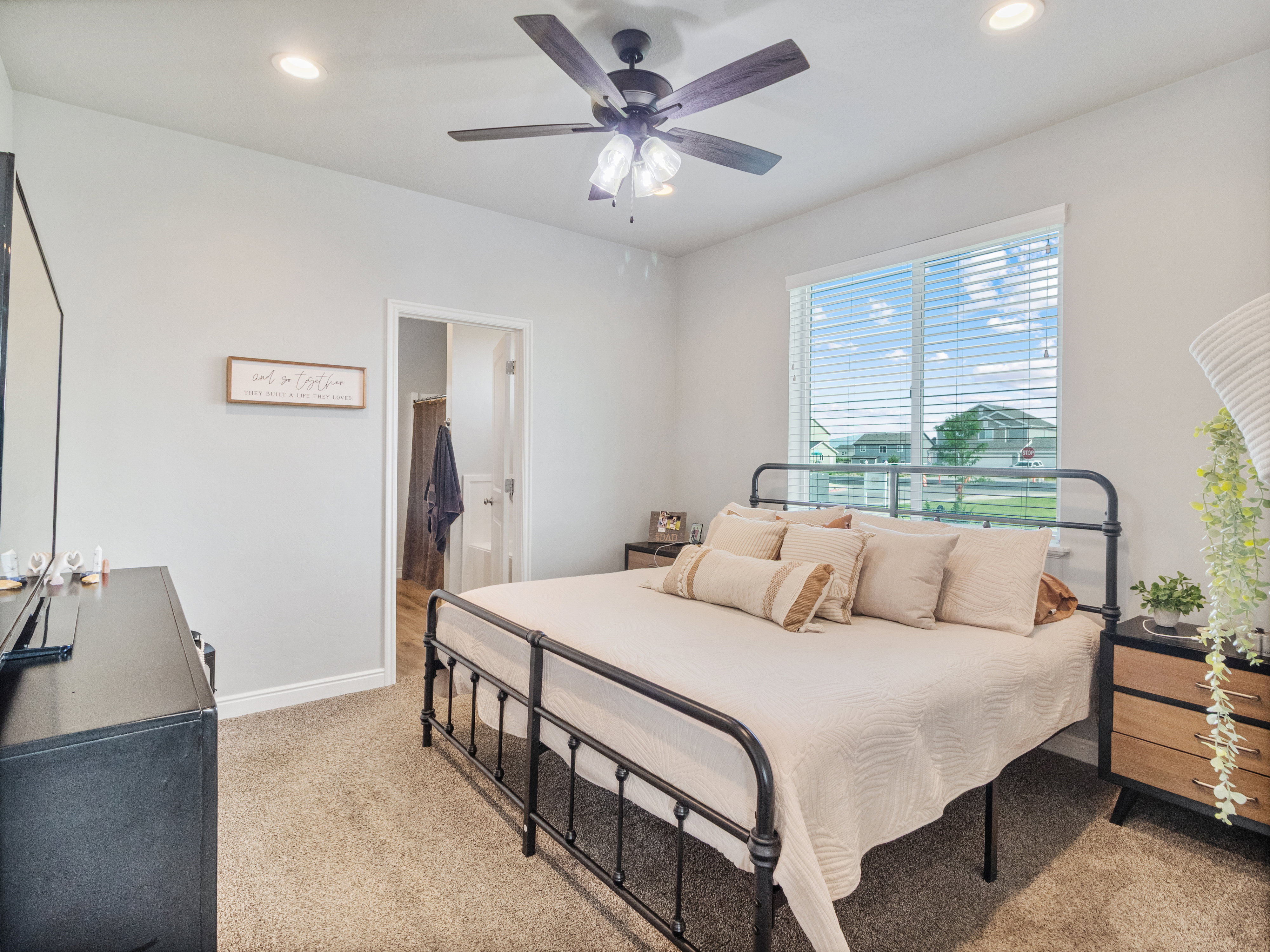 Carpeted bedroom with a large window featuring horizontal blinds