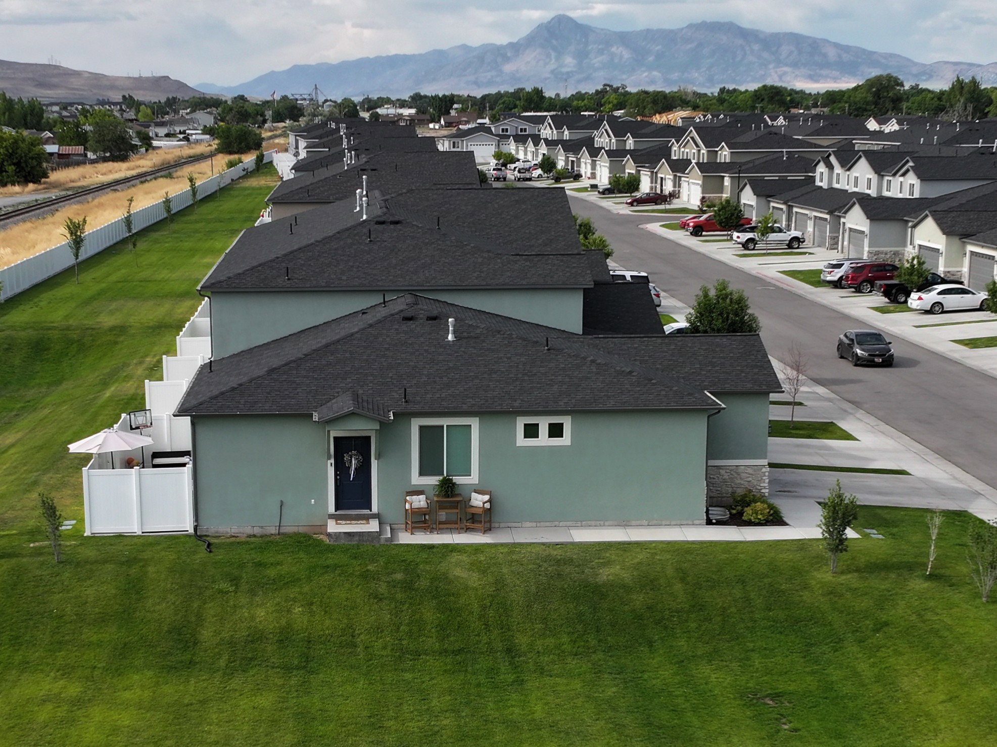 End Unit with Contemporary residential architecture featuring a dark shingle roof, light green siding, and a contrasting dark blue front door.
