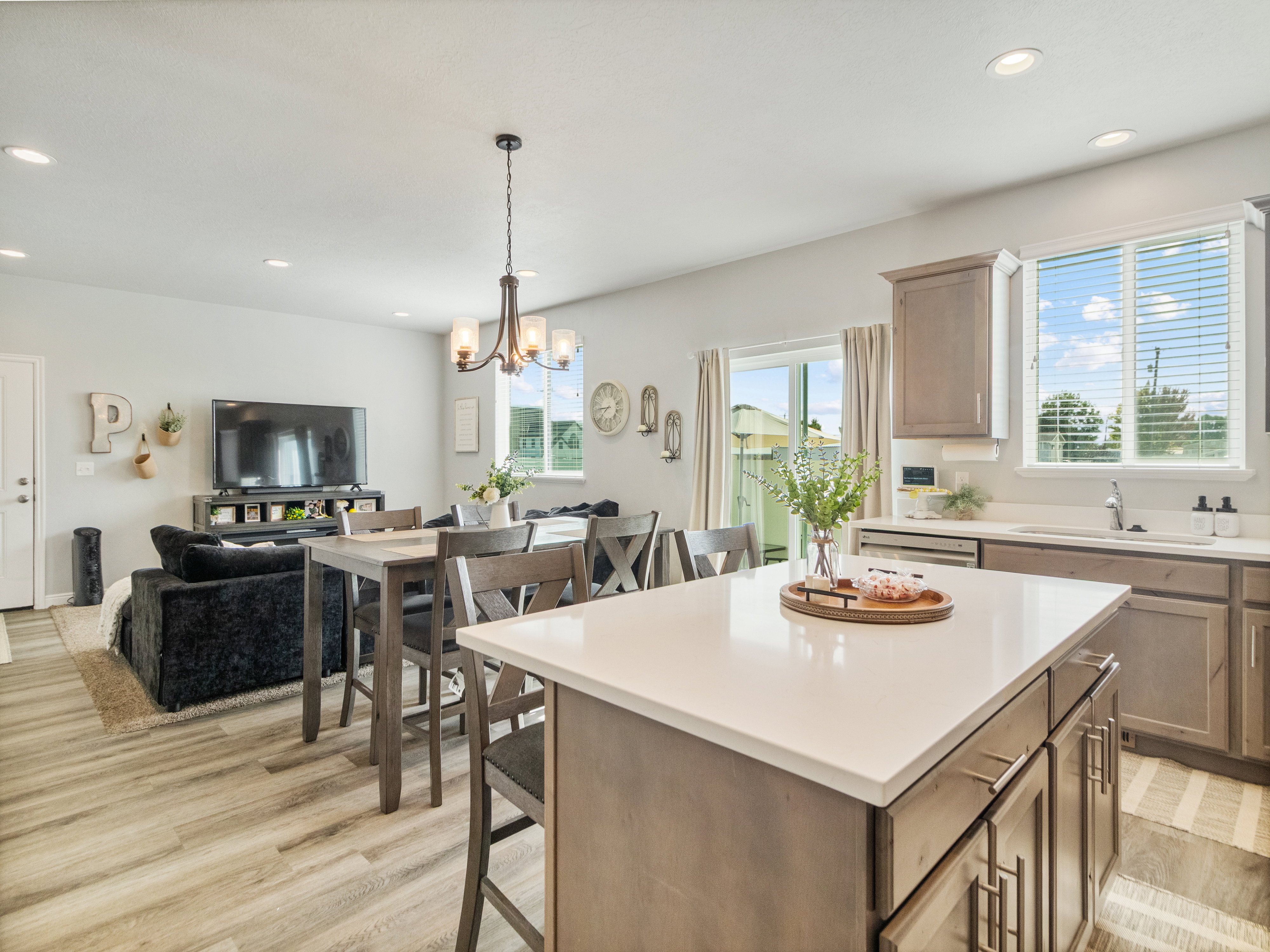 Spacious open-concept living area featuring wood-finish flooring, recessed lighting, and a modern kitchen island with a light-toned countertop