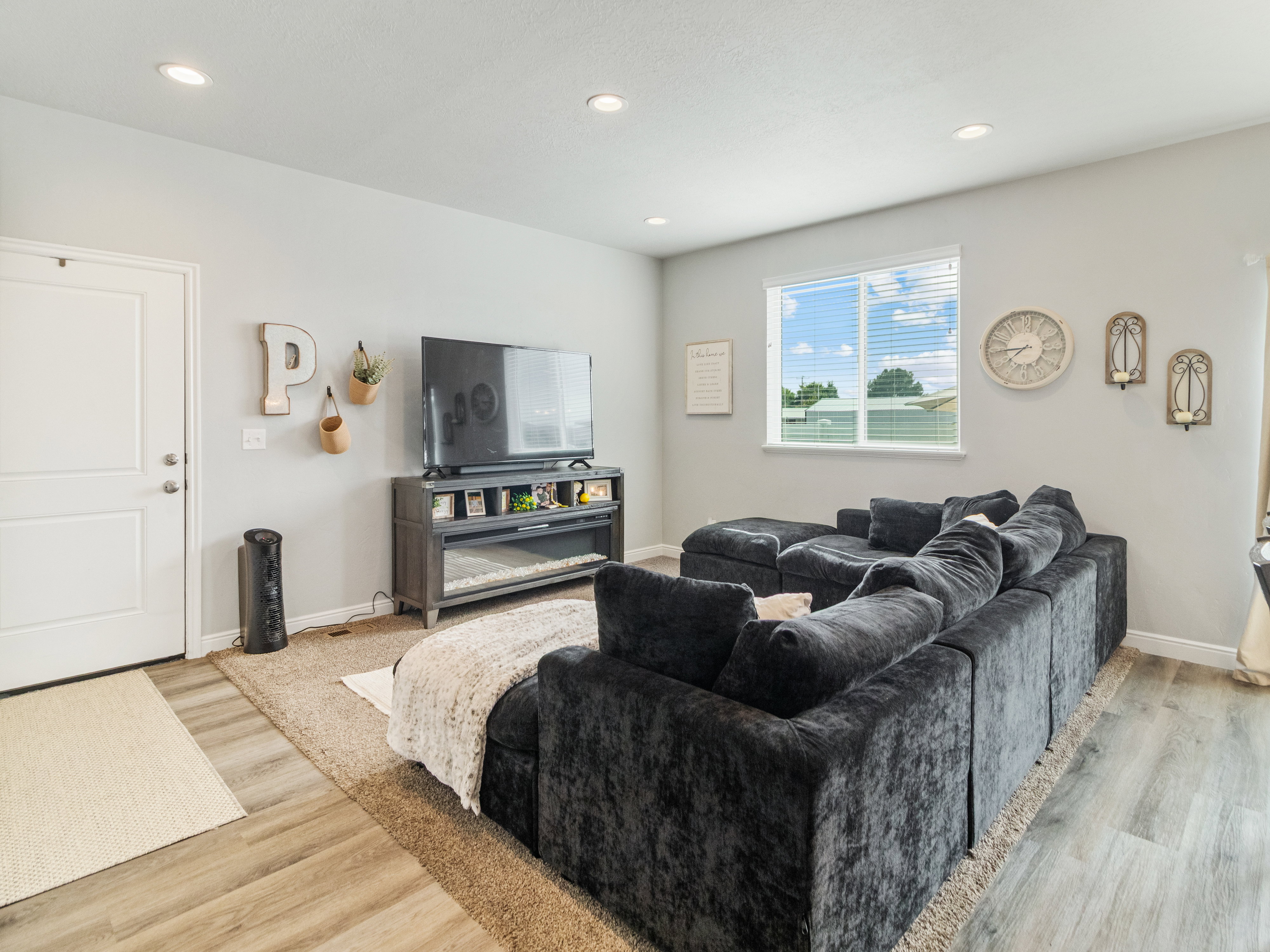 Open-concept living space with light wood-finish flooring, recessed lighting, and a white paneled door