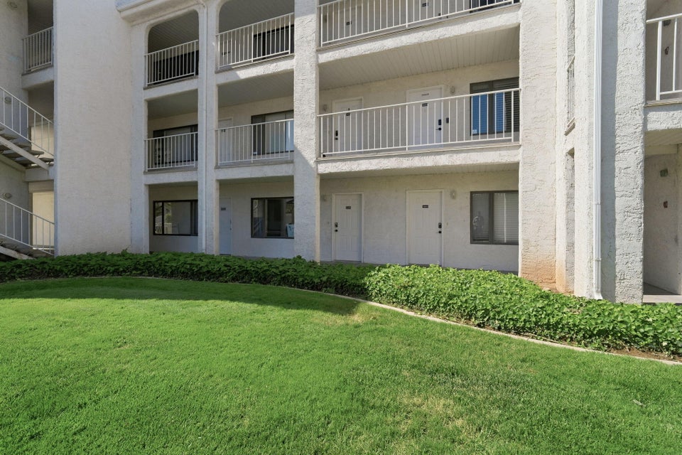 Multi-story building exterior with white stucco finish and individual balconies featuring white metal railings