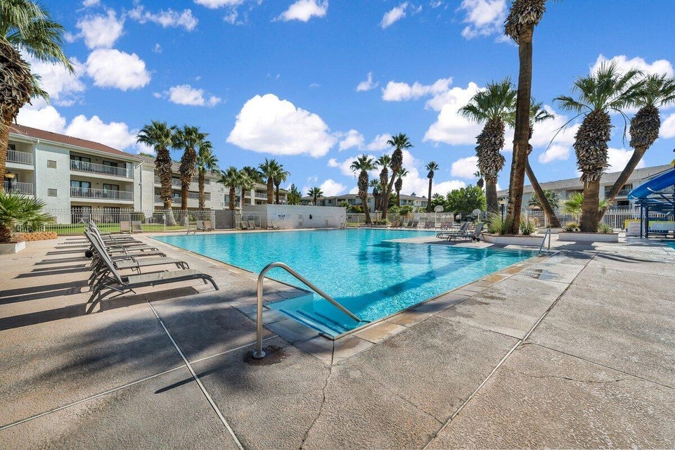 Spacious swimming pool with integrated steps and a stainless steel handrail, surrounded by concrete decking