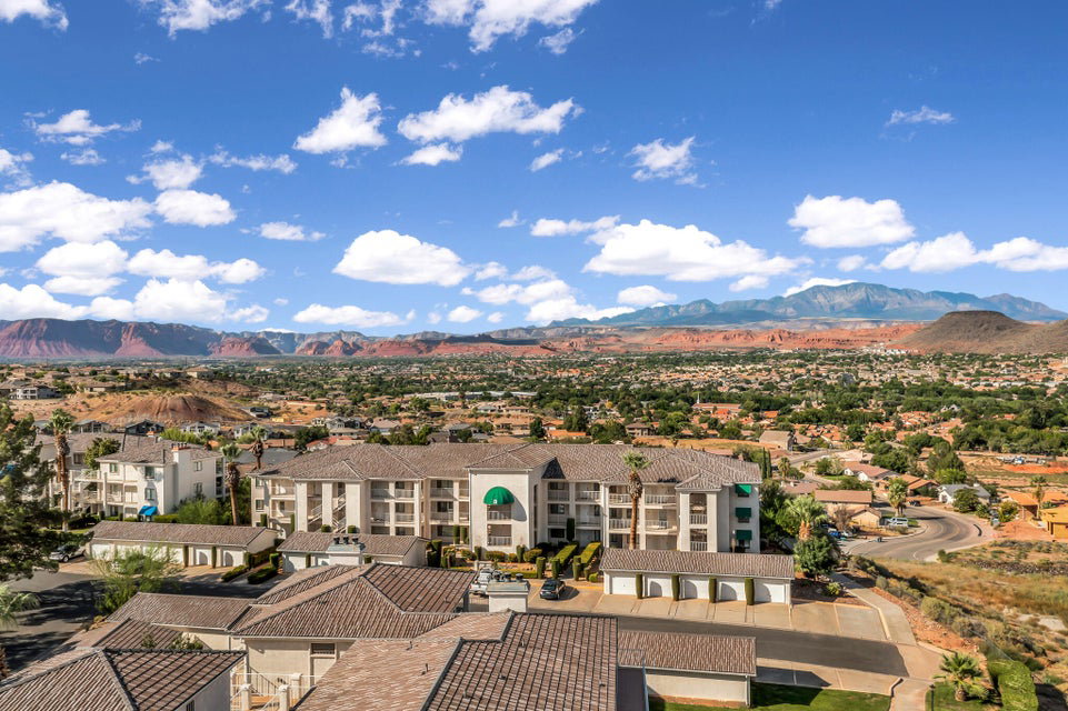 Expansive desert and mountain scenery frames a multi-story residential building featuring multiple balconies and green awnings