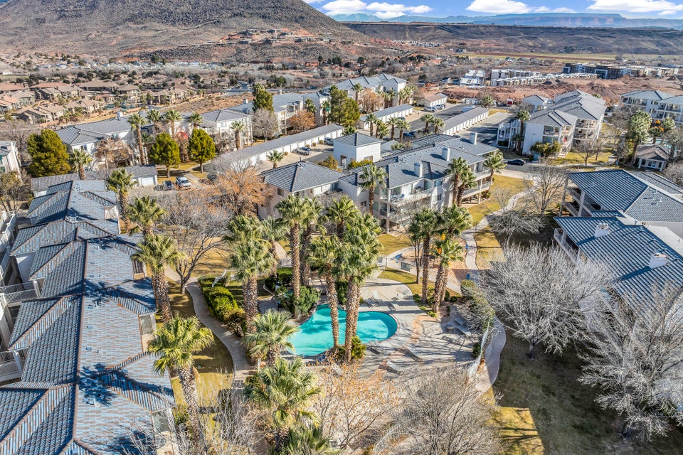 Community pool with surrounding palm trees, green spaces, and multiple residential buildings featuring balconies