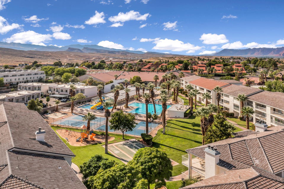 Expansive outdoor amenity area featuring multiple swimming pools, tennis courts, and a children's play structure
