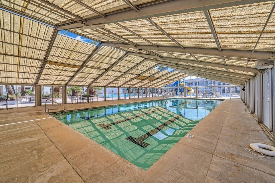 Covered swimming pool with lane markers, integrated handrails, and surrounding concrete decking