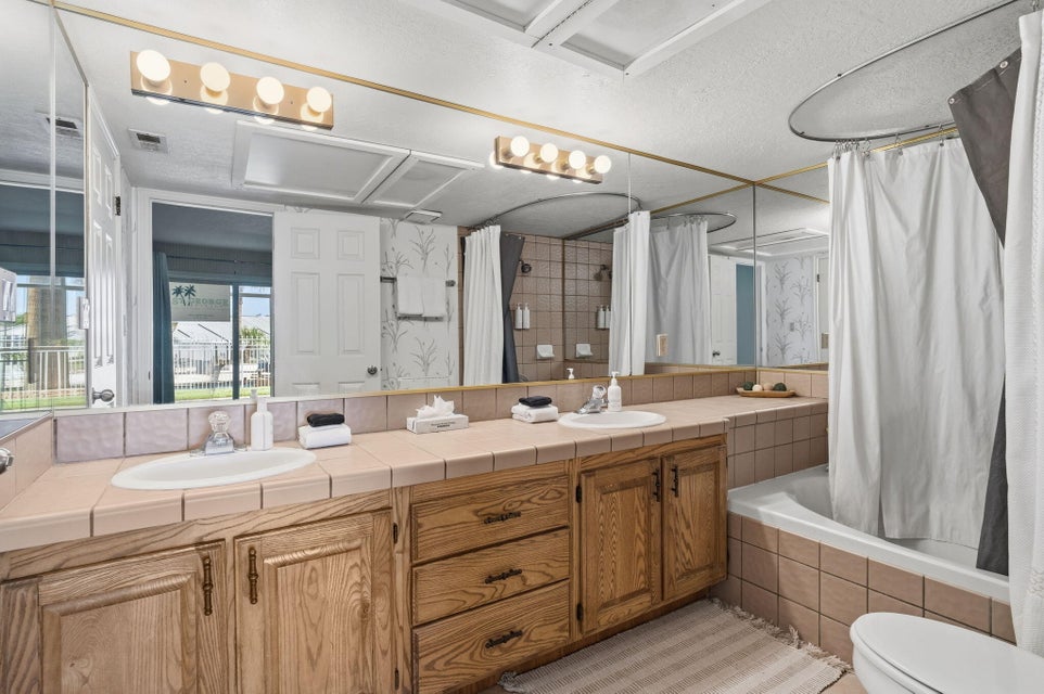 Bathroom featuring a dual vanity with tile countertop, wood cabinetry, and integrated sinks