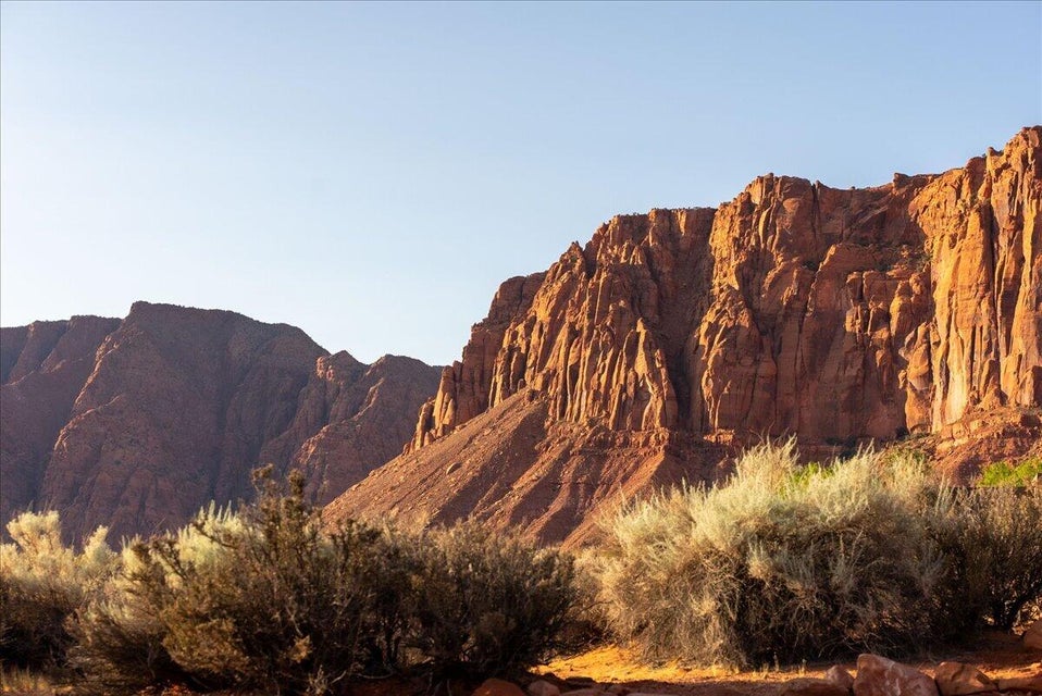 Expansive red rock geological formations with arid vegetation in the foreground