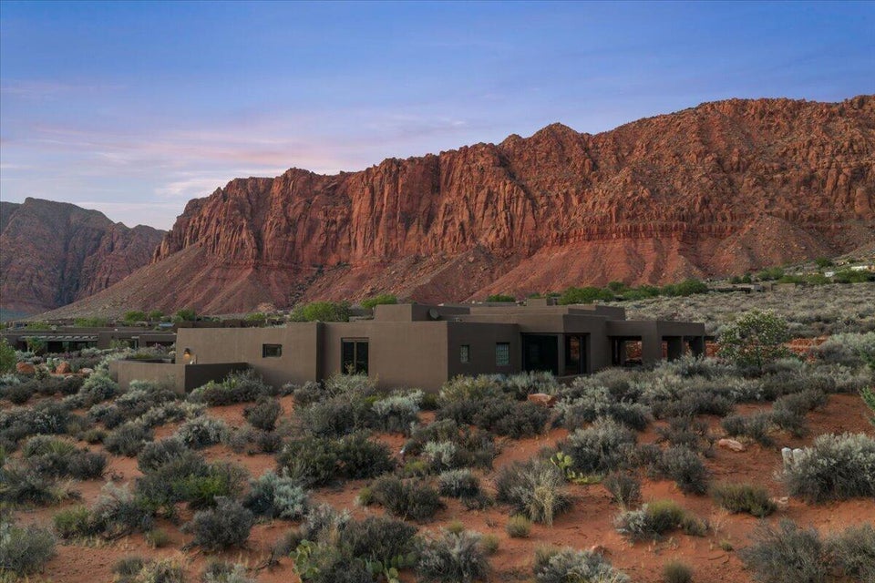 Contemporary flat-roof residence with a stucco exterior, integrated into a desert landscape with native vegetation