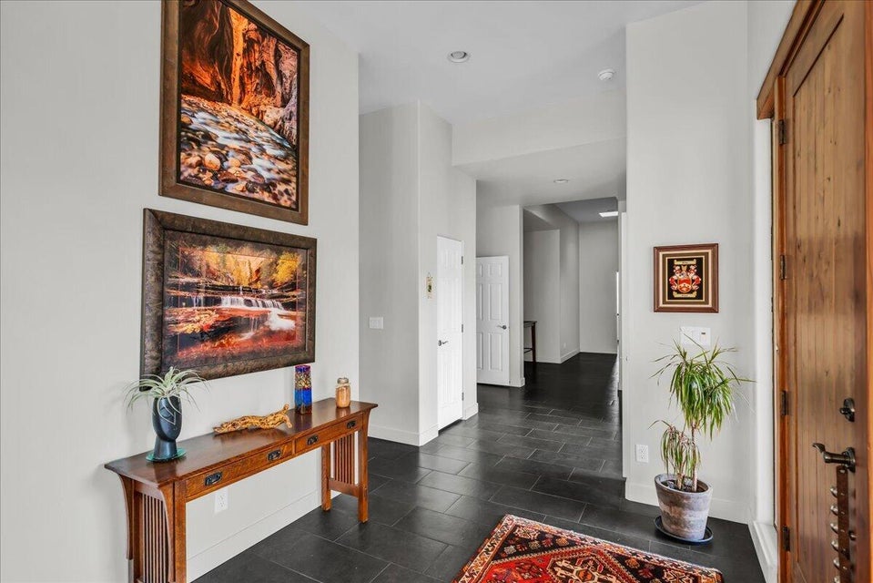Entryway featuring a solid wood door with wrought iron hardware, dark tile flooring, and light-toned walls