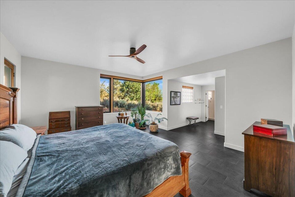 Spacious room featuring multiple large windows, dark tile flooring, light-toned walls, a built-in ceiling fan, and a wide entryway