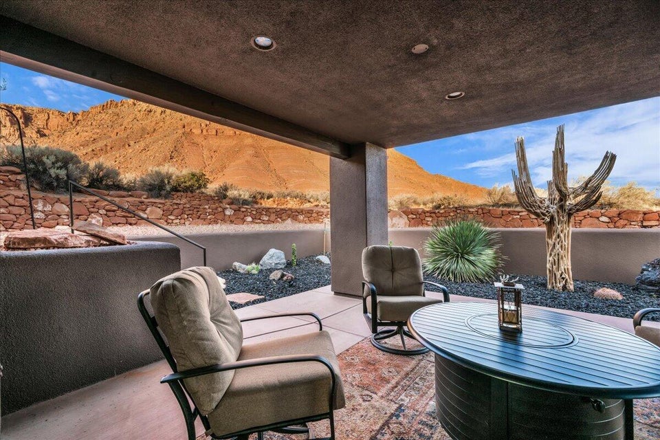 Covered patio featuring recessed lighting, a concrete floor, and a desert landscape with a rock wall