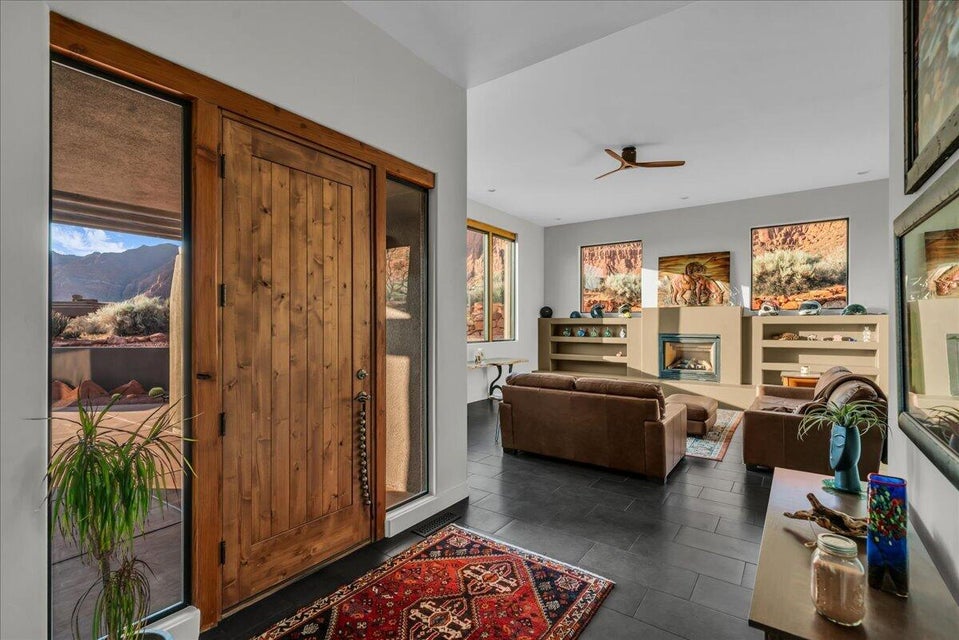 Entryway featuring a natural wood plank door with sidelight windows, dark tile flooring, and a decorative area rug