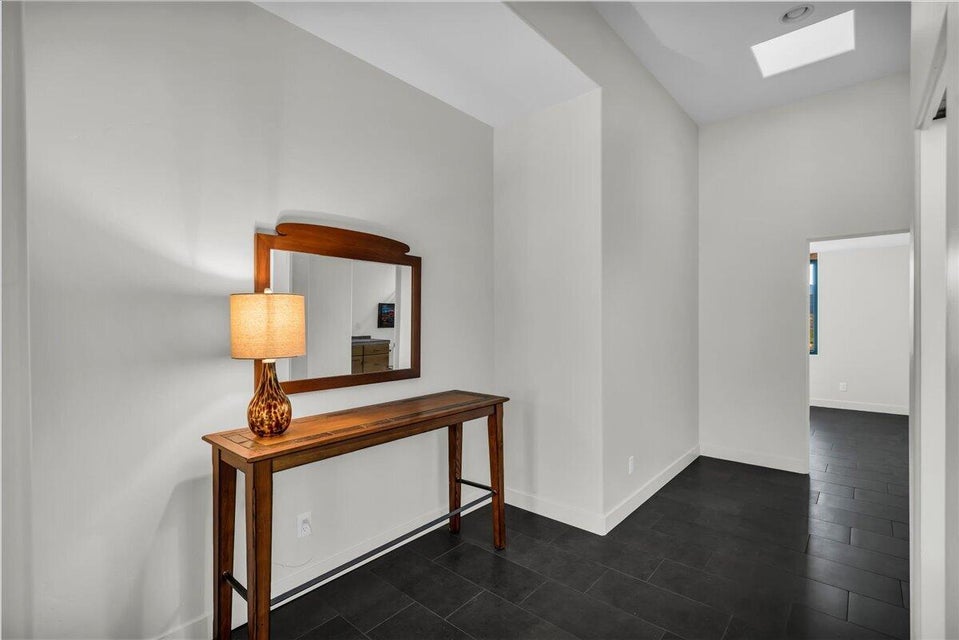 Foyer featuring dark rectangular floor tiles, white walls, and a high ceiling with a skylight
