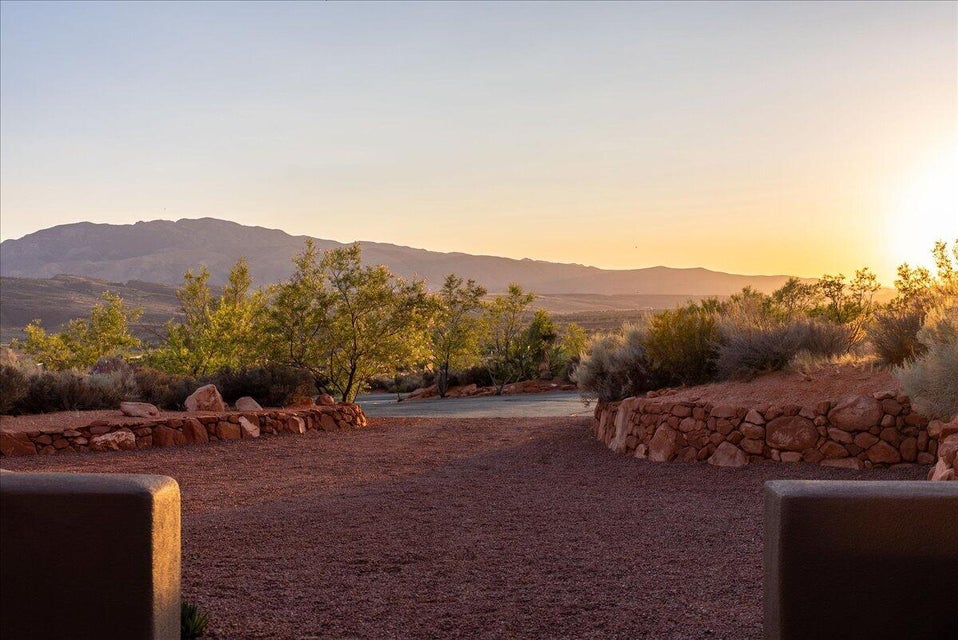 Expansive gravel yard with low rock wall landscaping and indigenous plantings