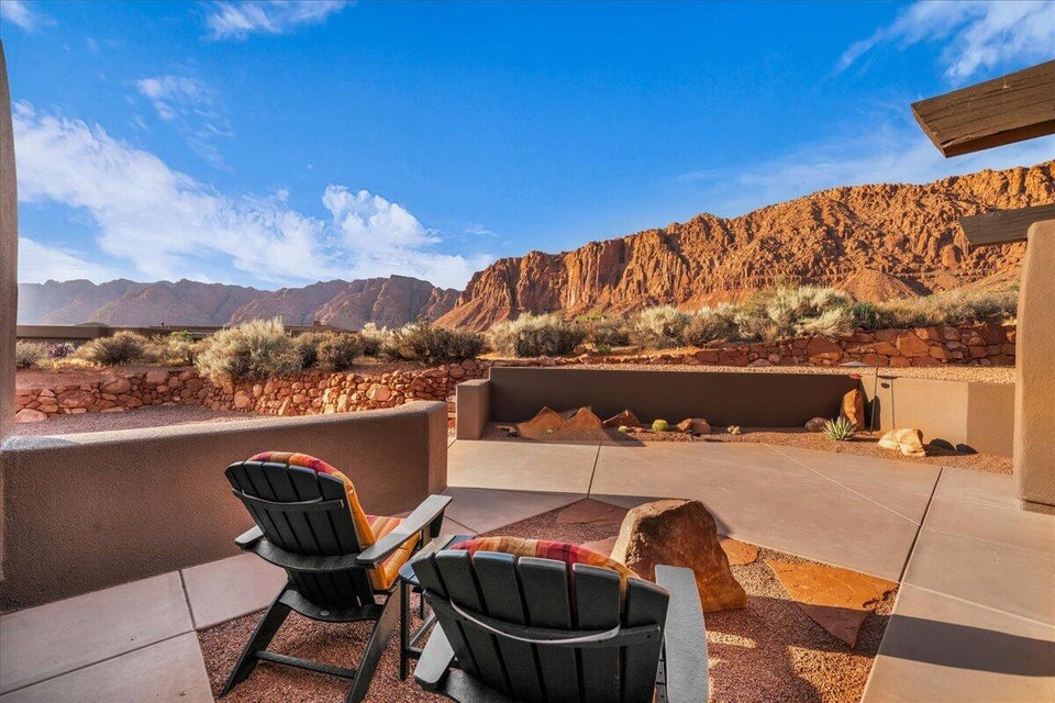 Expansive patio with desert landscaping and natural rock features, complemented by a large concrete pad and gravel ground cover