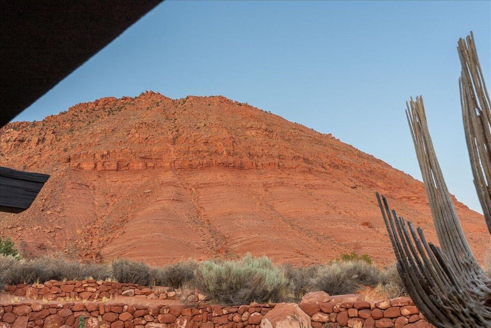 Natural desert landscaping with a rock retaining wall, featuring a prominent red rock mountain backdrop under a clear sky