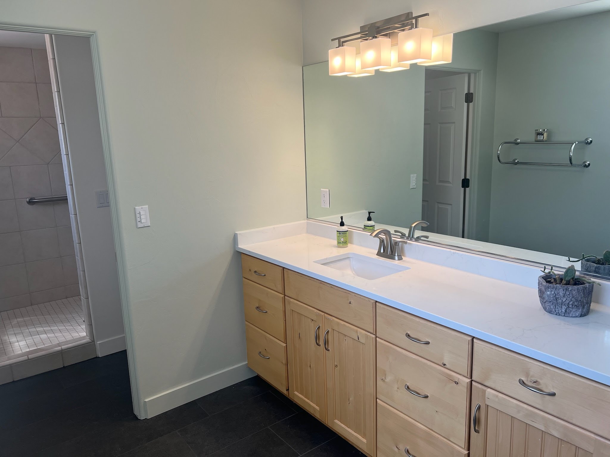 Bathroom featuring an expansive vanity with natural wood-finish cabinetry, a white countertop, and an integrated sink