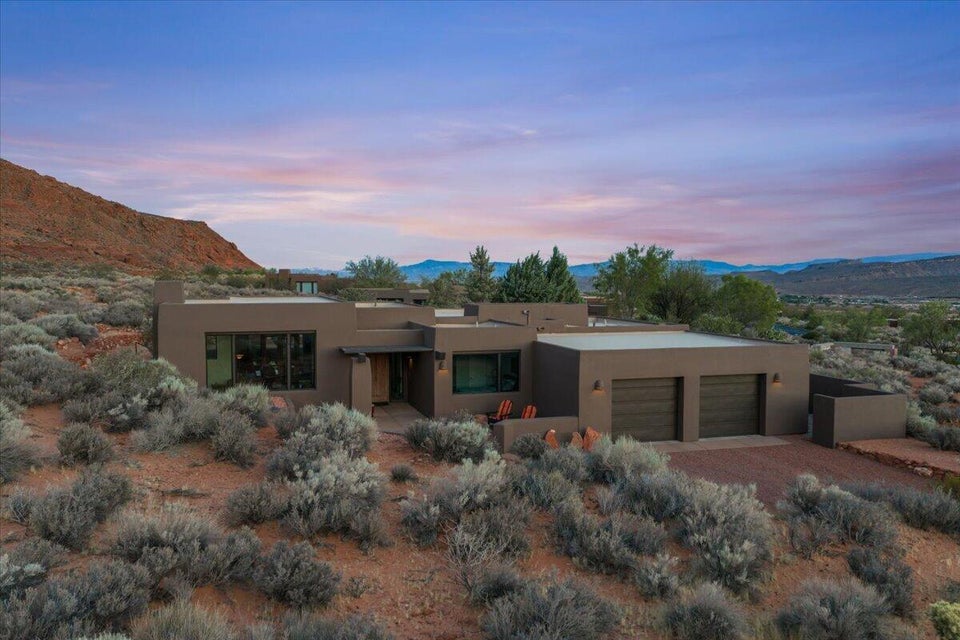 Modern stucco exterior with a flat roofline, integrated two-car garage, large picture windows, and a covered entry