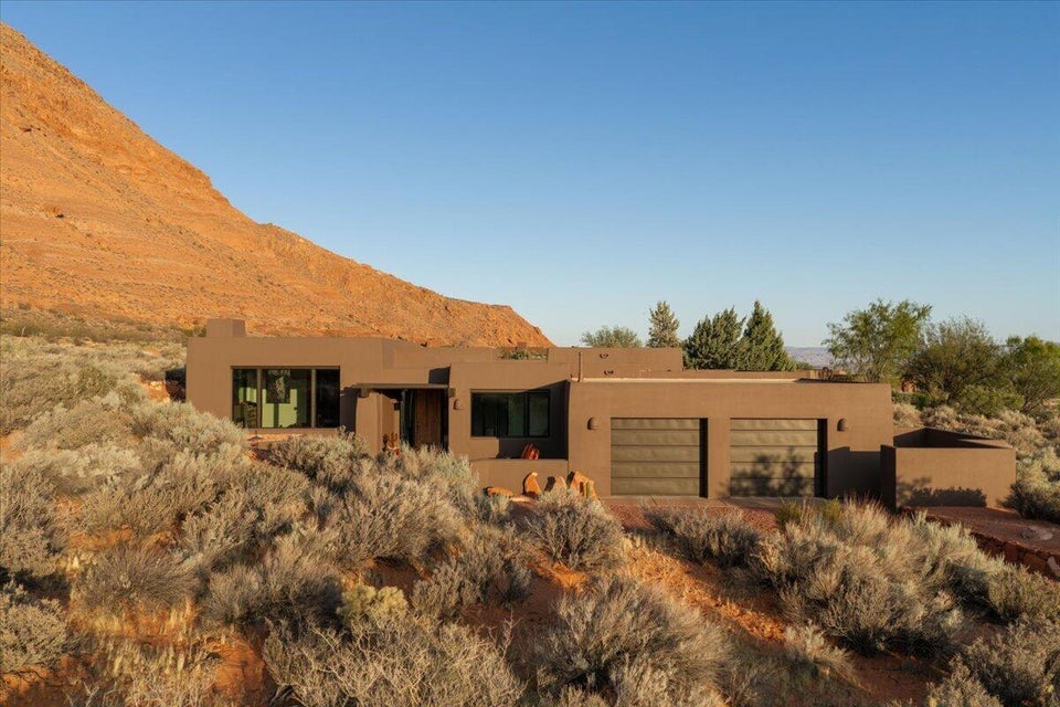 Contemporary stucco exterior featuring a two-car garage with modern doors, integrated entry porch, and large windows