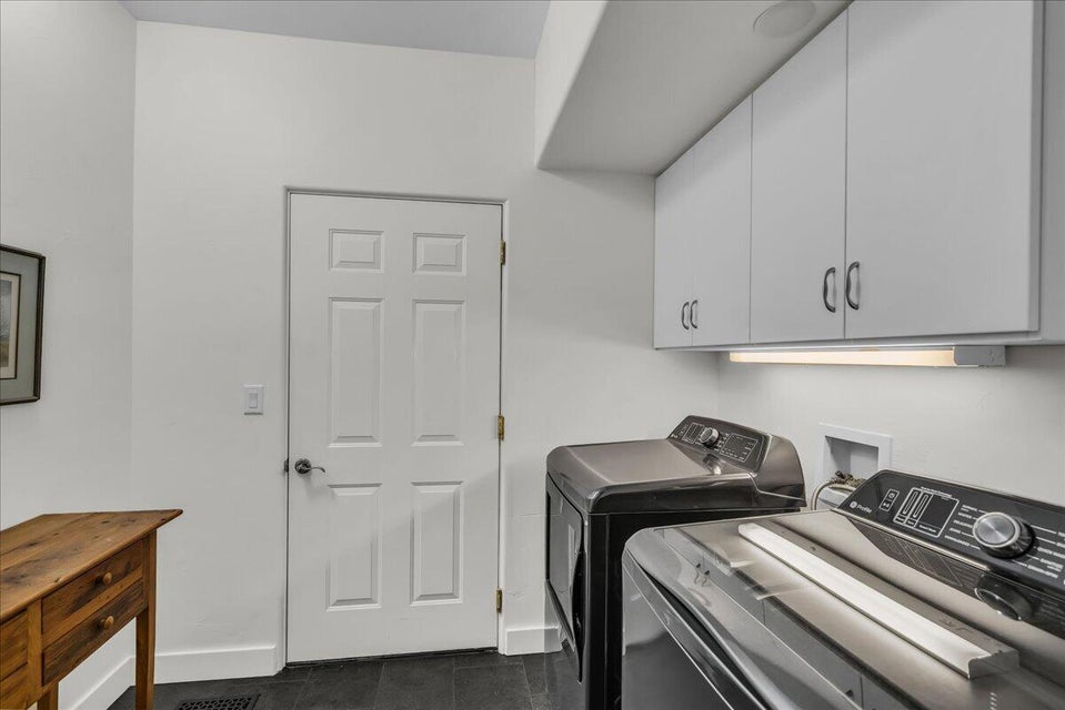 Dedicated laundry area with dark flooring, white walls, and bright overhead lighting