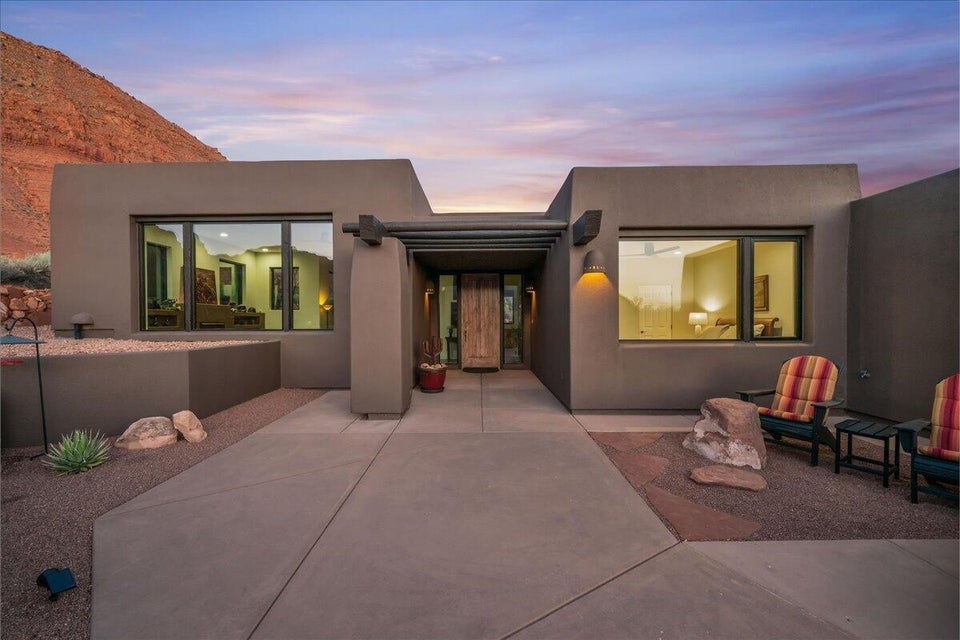 Modern stucco exterior with large windows, a striking wood entry door, and a decorative pergola accent