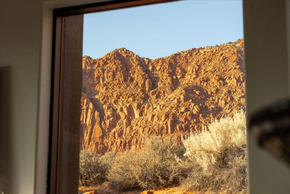 Expansive mountain rock formations with desert foliage visible through a dark-framed window