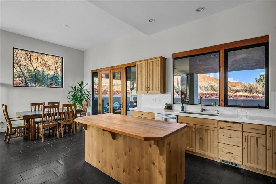 Expansive kitchen featuring a wood-finish island with a butcher block top, natural wood cabinetry, a white countertop, and a subway tile backsplash