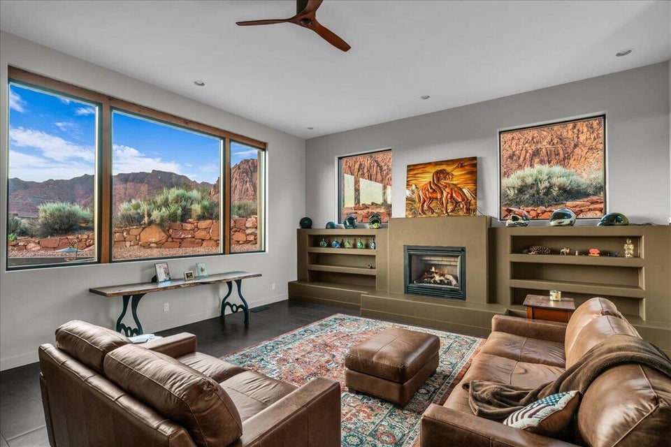 Living area featuring large picture windows with wood-finish frames, a built-in fireplace, and integrated shelving