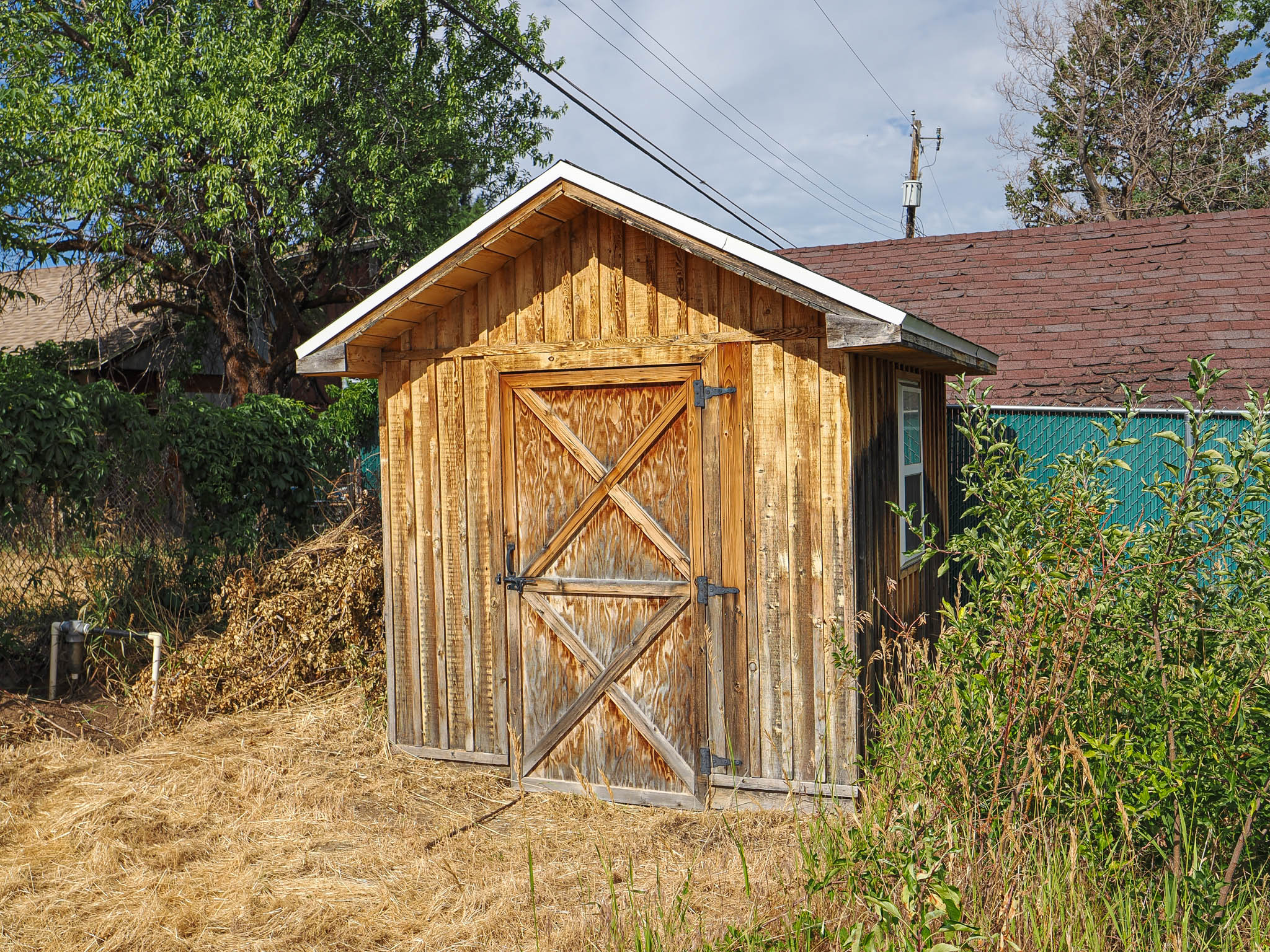 Wood-paneled shed with a gambrel roof and barn-style doors