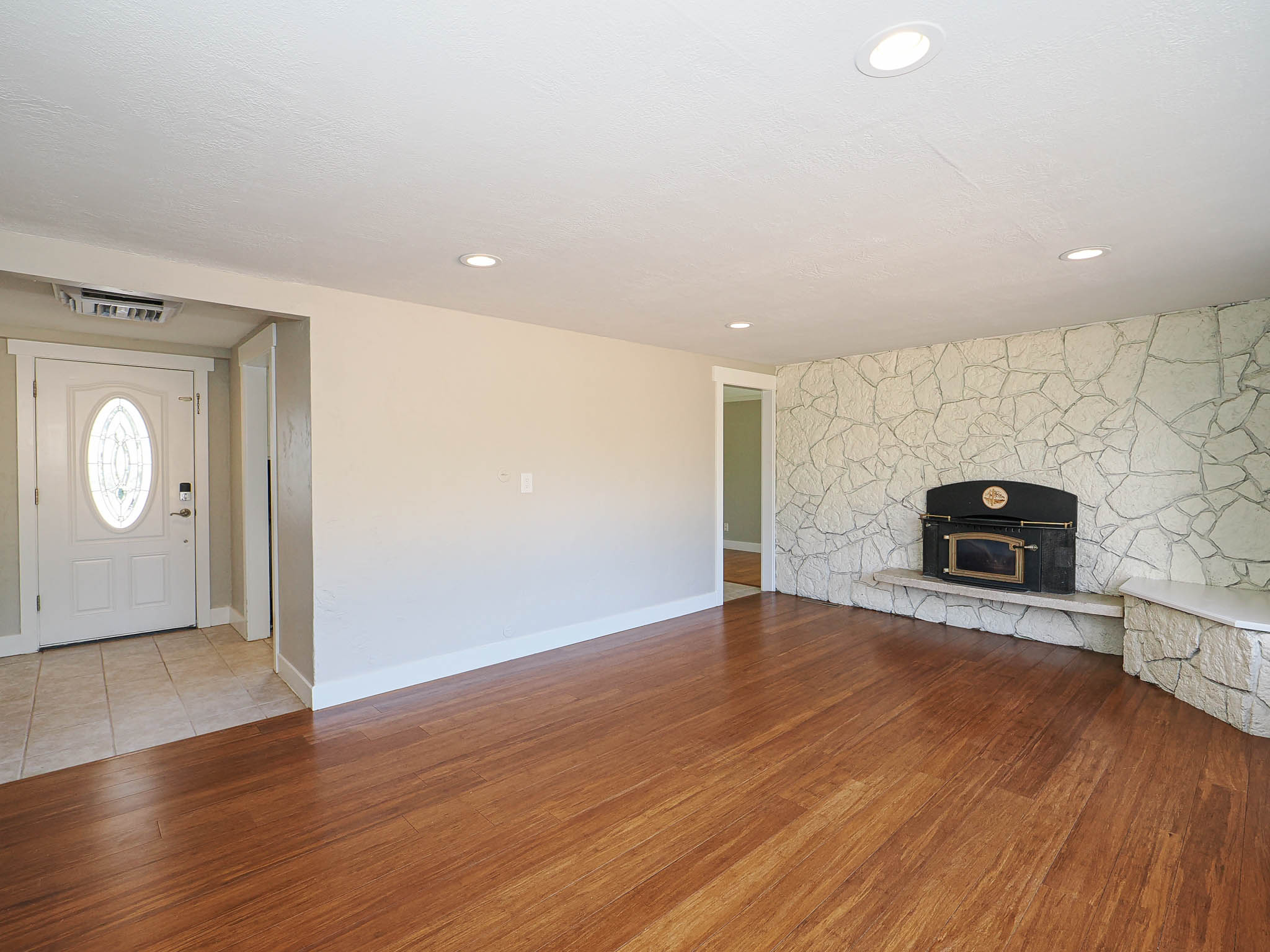 Living area featuring wood-finish flooring, recessed lighting, and a stone accent wall with a built-in fireplace