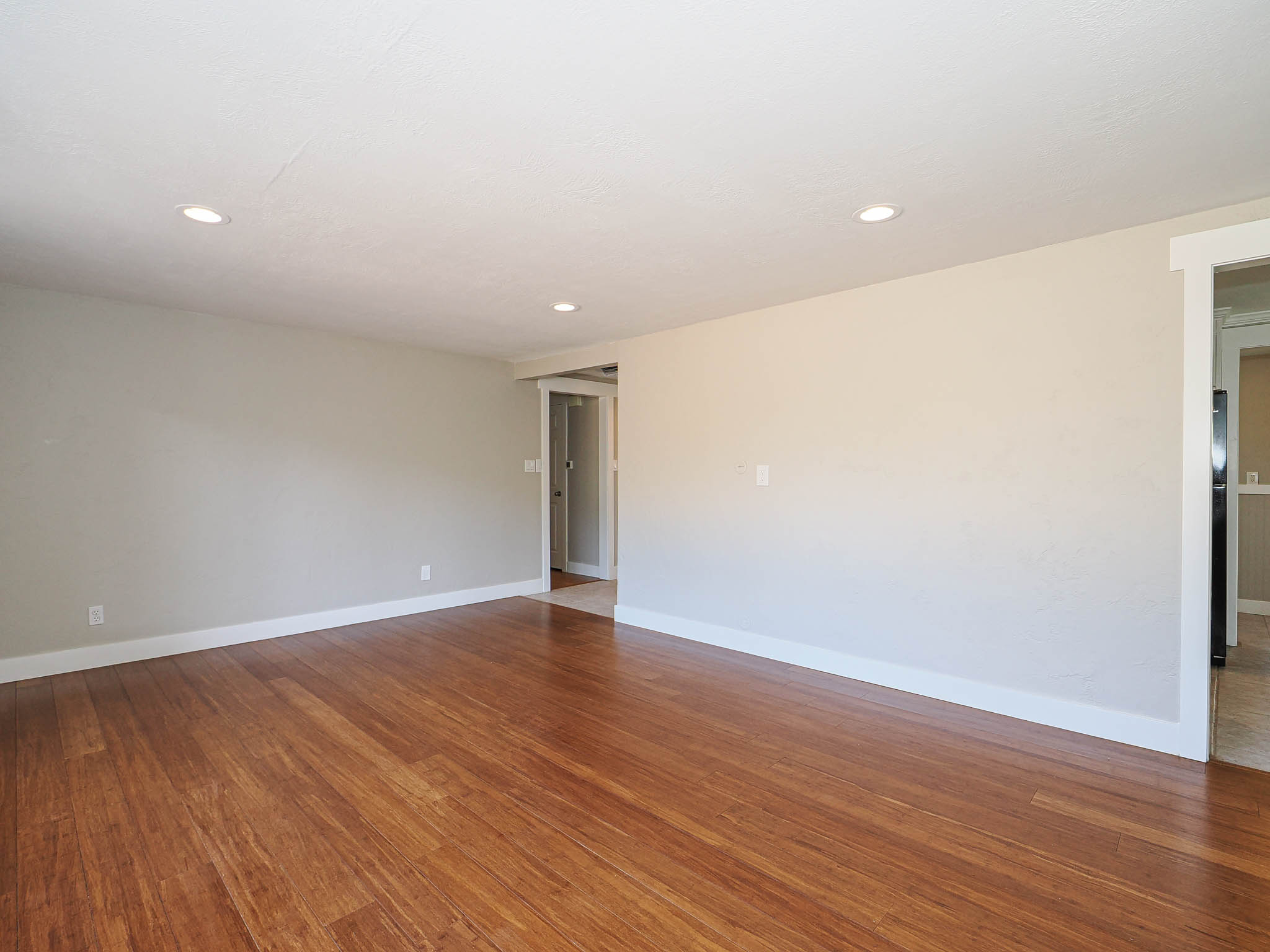 Spacious room featuring wood-finish flooring, recessed lighting, neutral wall tones, and white trim molding