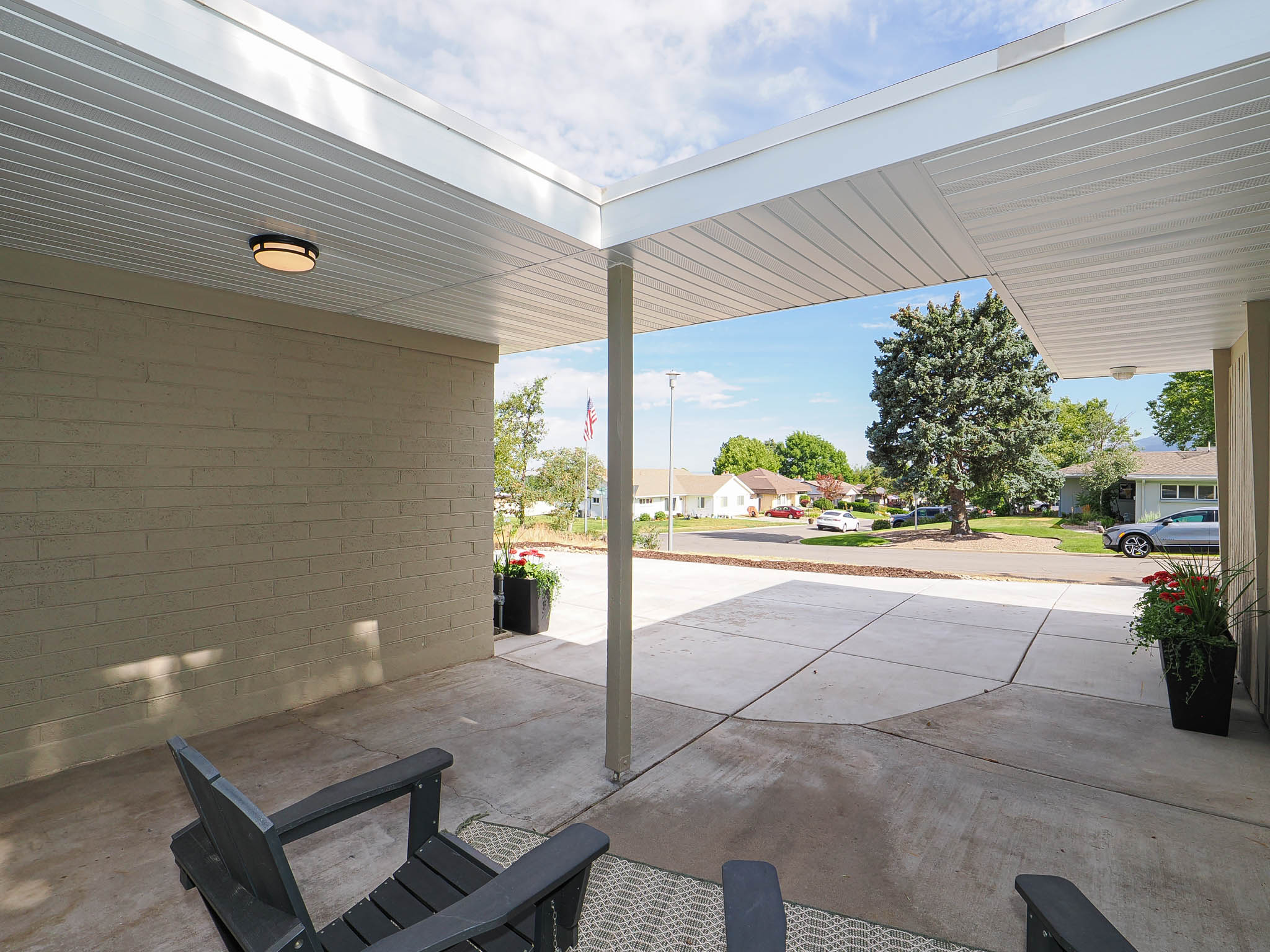 Covered concrete patio featuring a brick exterior wall, recessed lighting, and a paved driveway