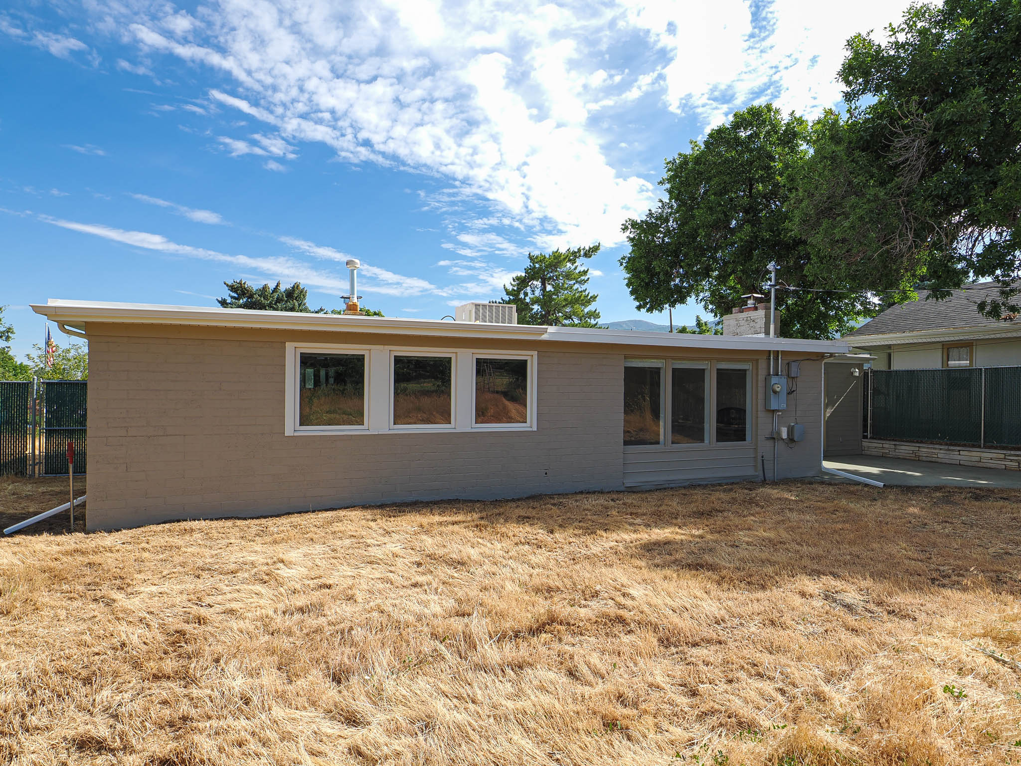 Rear exterior featuring a flat roofline, neutral-toned siding, and multiple large windows