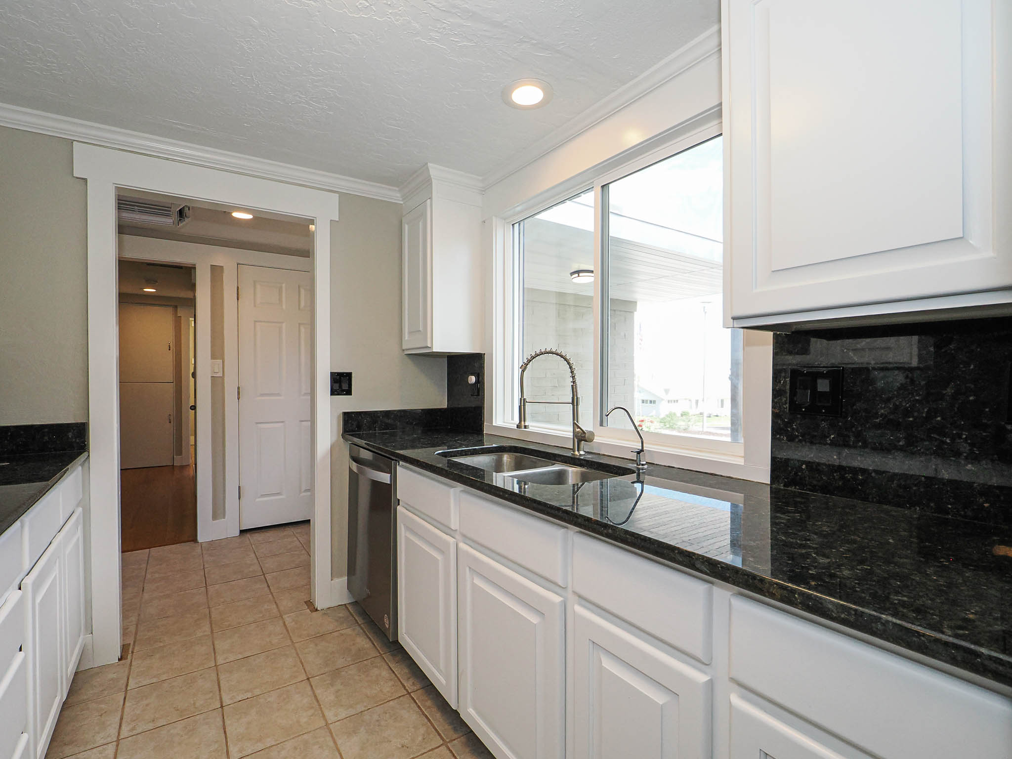 Kitchen featuring white cabinetry, dark stone countertops, stainless steel sink with gooseneck faucet, and recessed lighting