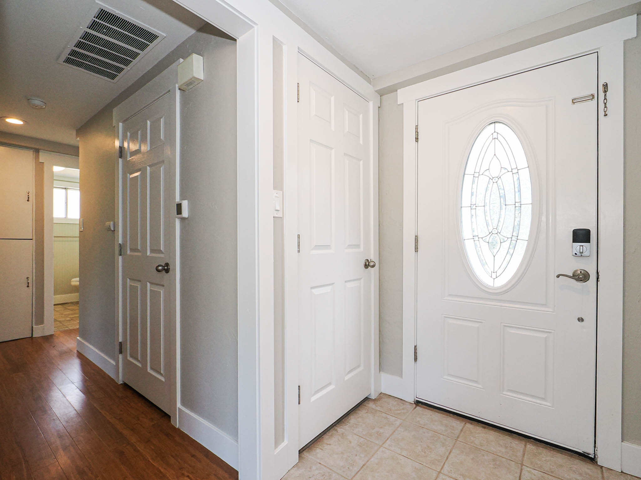 Entryway featuring a white paneled door with an oval stained-glass insert, a digital lock, and tile flooring