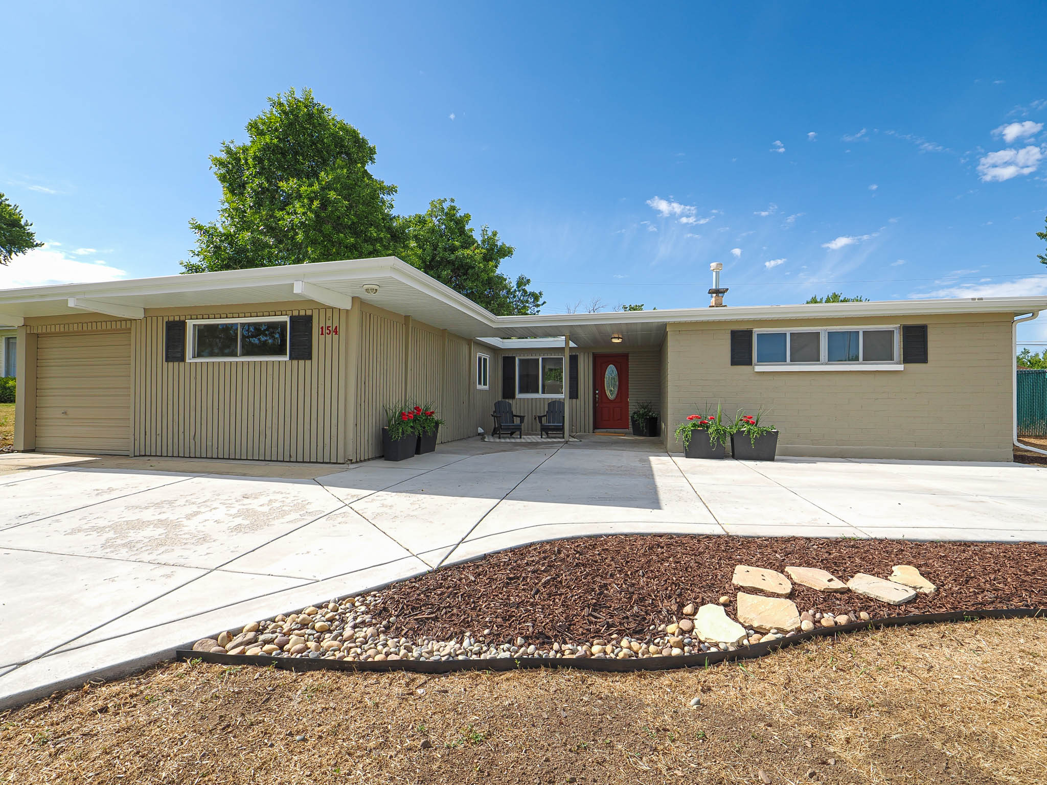 Mid-century modern ranch featuring a red entry door, horizontal slat siding, and brick veneer facade