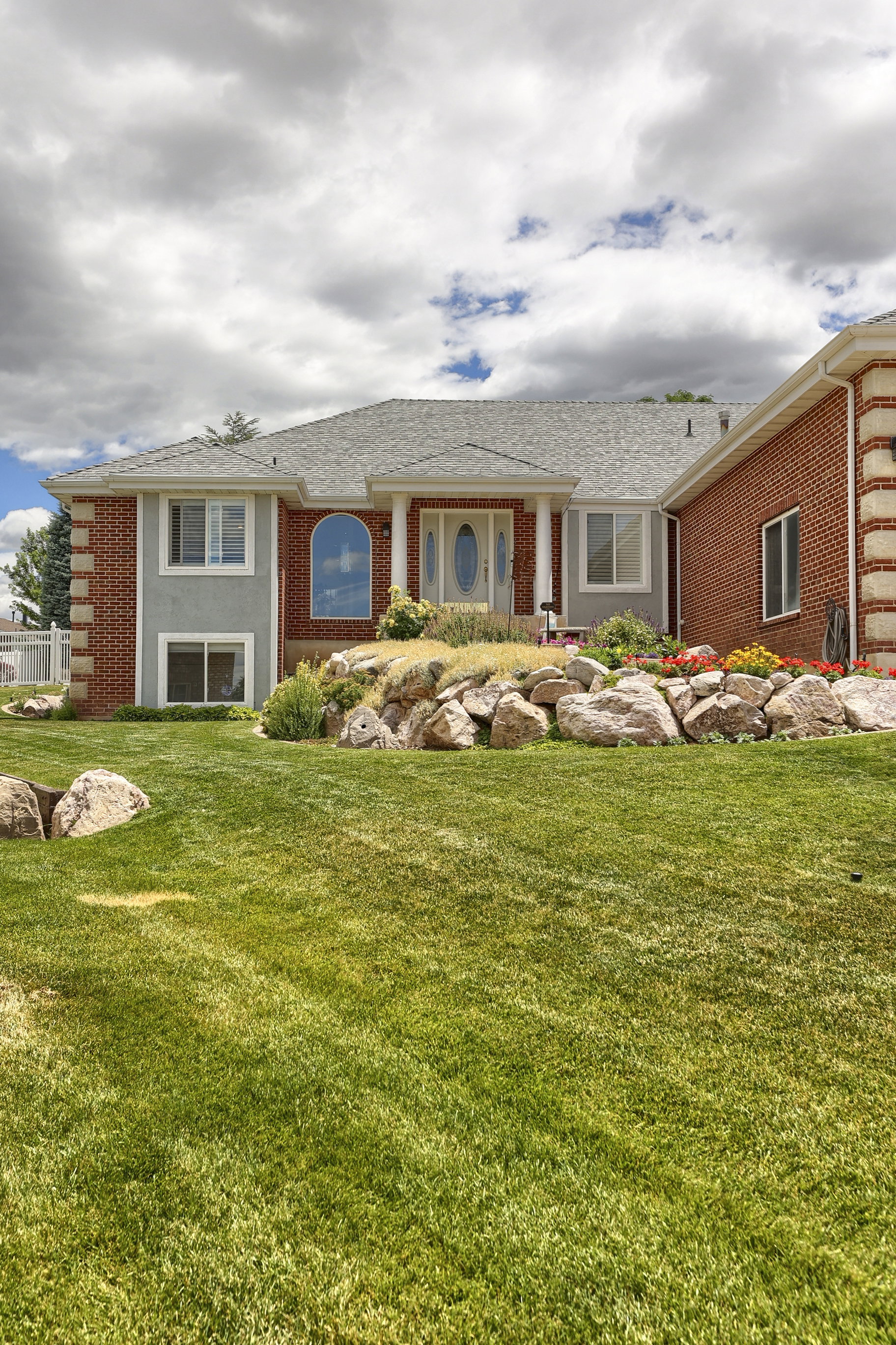 Brick and stucco exterior featuring a prominent arched window and a covered entry with columns