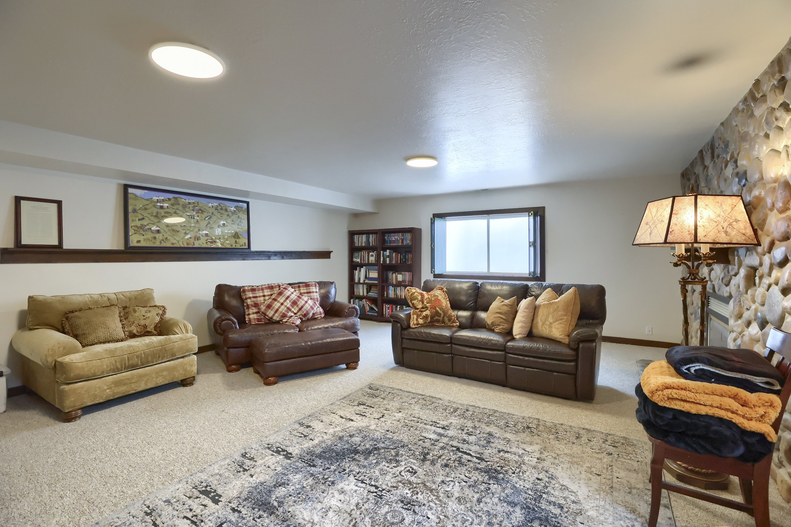 Carpeted living area featuring a stone accent wall, recessed lighting, and a built-in bookshelf