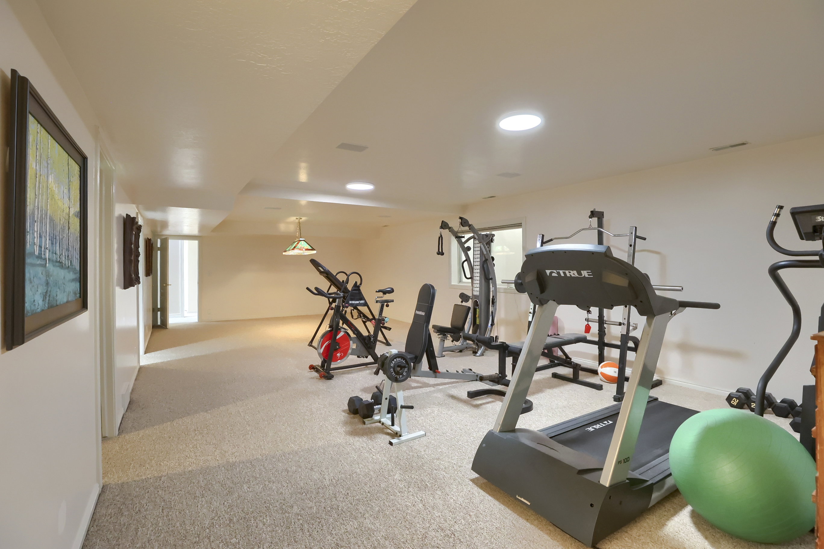 Expansive carpeted room featuring recessed lighting, a drop ceiling with integrated circular lights, and neutral-toned walls