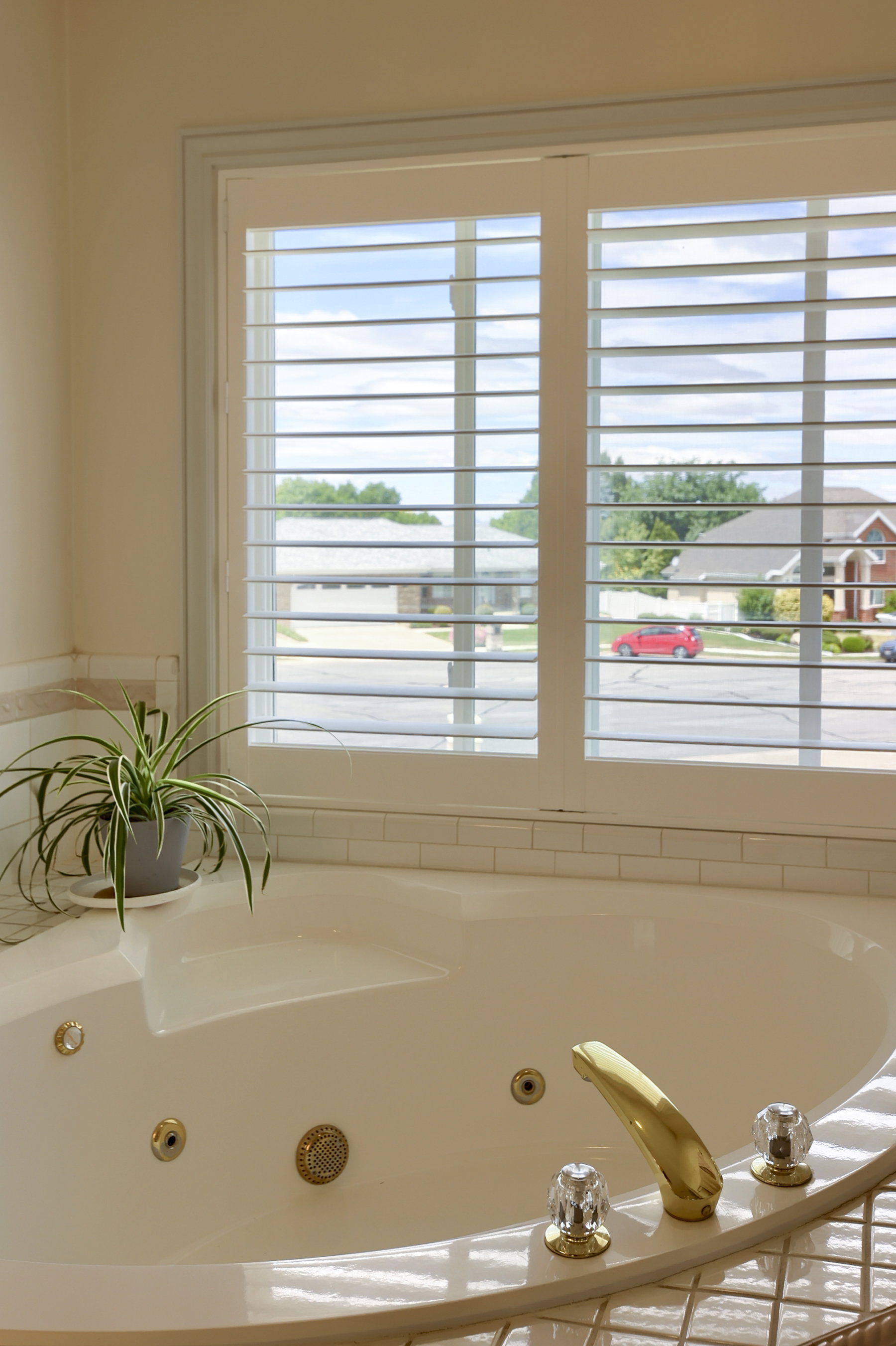 Built-in soaking tub with gold-tone fixtures and clear acrylic handles